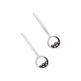 Load image into Gallery viewer, Pair of hand fabricated earrings in sterling silver, featuring a 10-millimeter circle connected to a 2-inch long rectangular bar with an ear post. The lower half of each circle has an array of asymmetrical silver balls of various sizes intricately nested. The circles' interiors showcase a sleek blackened and high polished finish, while the exteriors are a brushed matte luster. Both earrings laying on their back, and positioned next to each other on a white background.
