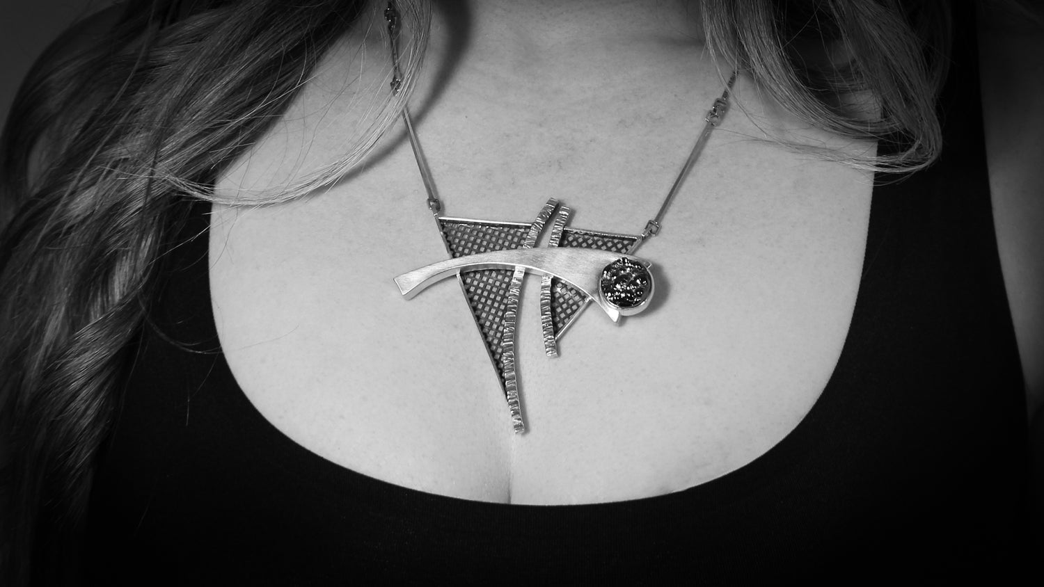 A slideshow of black and white photos of the artist wearing various pieces of jewelry. The pieces are made of silver, have a unique, modernist design, using geometric shapes and abstract designs.