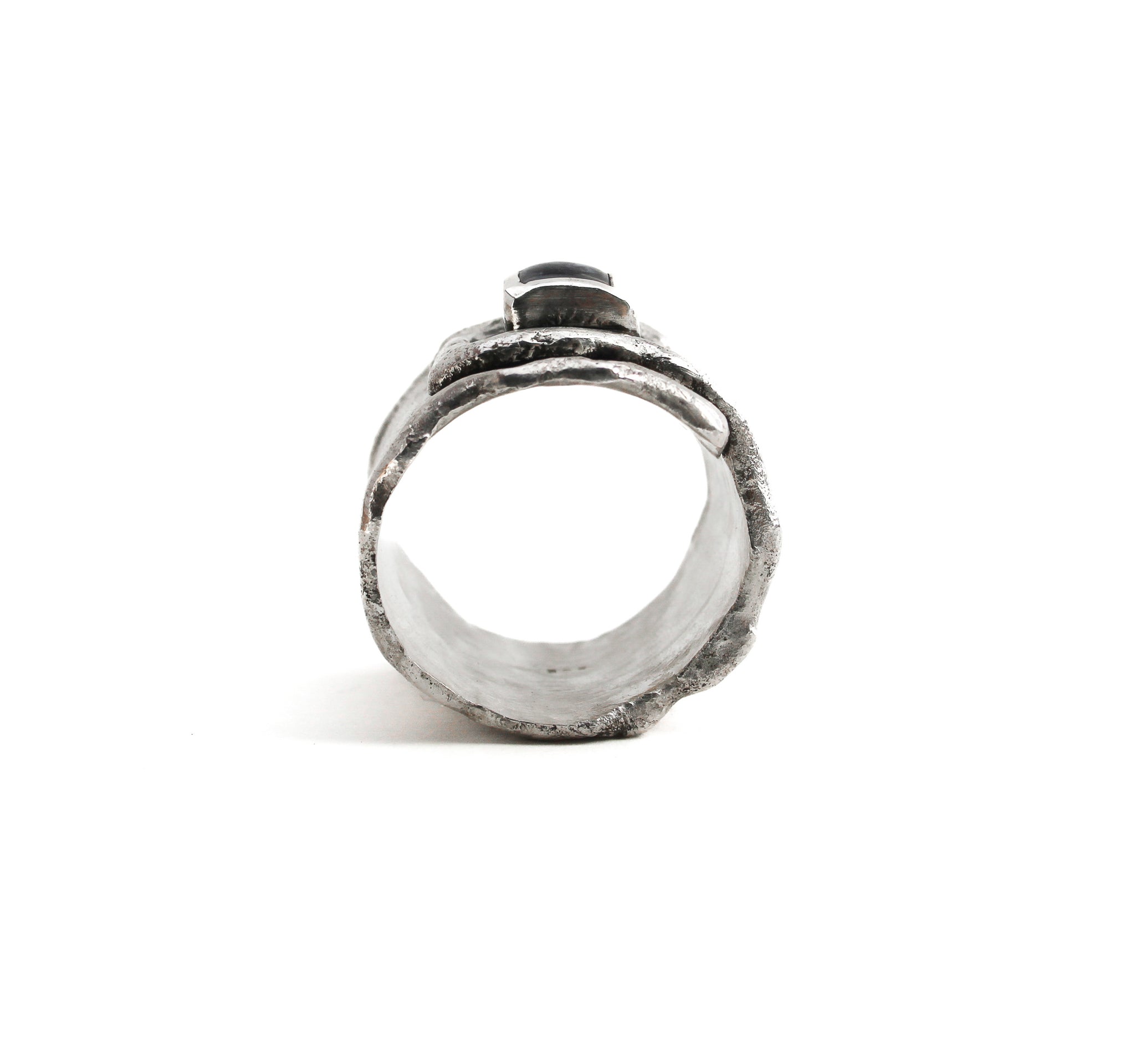 Sterling silver overlapping wrap ring, with melted edges and an oxidized rustic surface texture. Ring is on its side, showing the interior of the band and the profile of the square, translucent, blue moonstone roughly bezel set in the center of the ring.