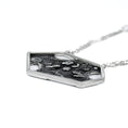 Load image into Gallery viewer, Laying flat side view of a contemporary sterling silver pendant, showing the right, outside edge of an asymmetric hexagon, made of thick square wire. The blackened backplate is slightly visible. The pendant is attached to a square link chain, that is blurred to view.
