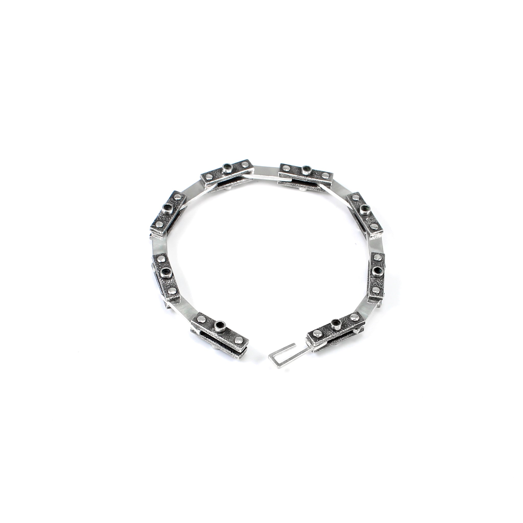 Unique industrial sterling silver bicycle-style chain bracelet. Every other link features a textured black finish with a 3mm tube soldered in the center on both sides and the alternate link is smooth and polished. Each link is connected by roughly finished rivets. Top down view, bracelet is undone and the hook clasp is visible.  