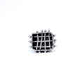 Load image into Gallery viewer, Front view of a brutalist inspired ring featuring a roughly crafted rectangle frame with three horizontally and four vertically positioned silver bars, creating a cage-like structure. The bars are intentionally bent and marred, piercing through the walls of the rectangle frame, with silver balls on either end holding them in place. The back of the cage is entirely black, providing a striking contrast
