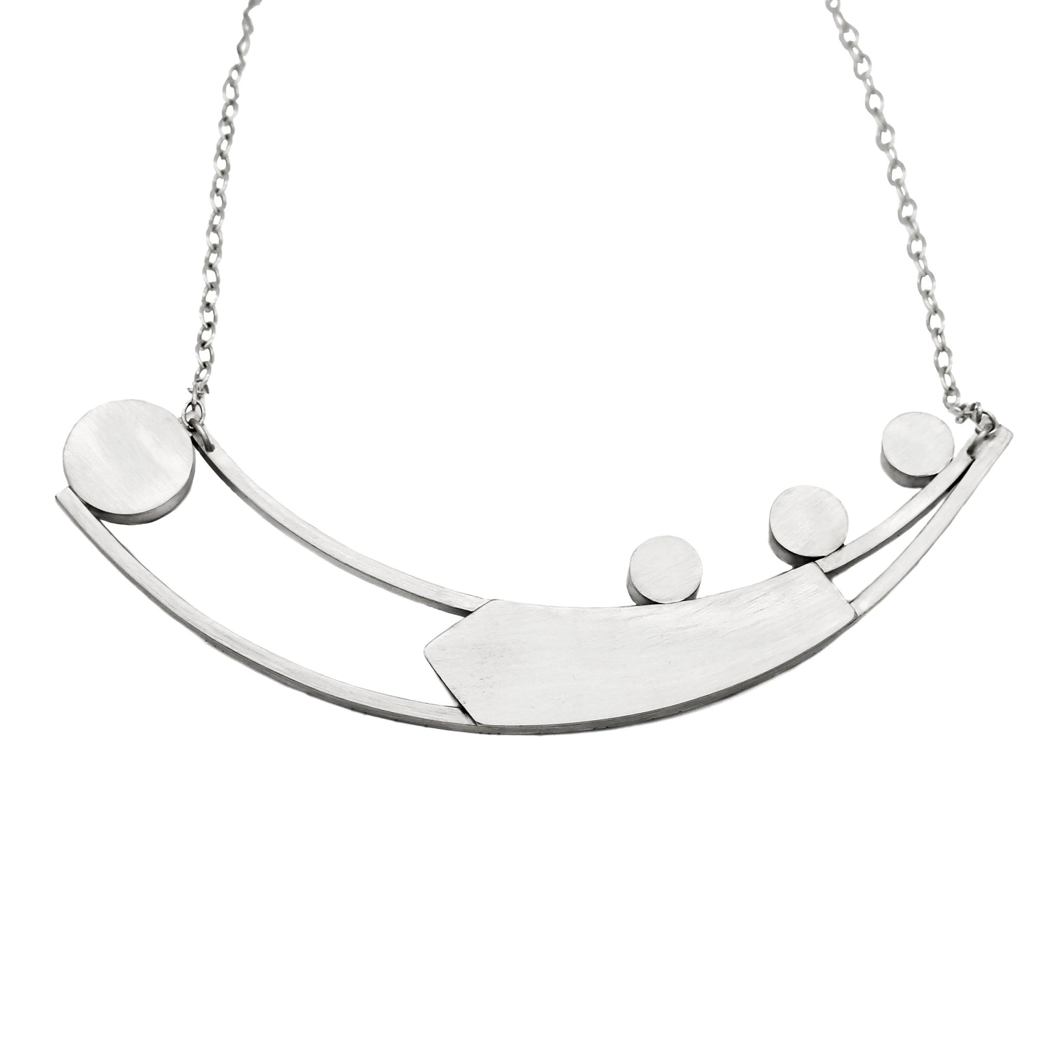 Back of necklace crafted from two long curved square wires connected at one end and split at the other. An angular sheet of silver is positioned between the wires. On the right side of the top curved bar, three 10-millimeter stones are set and on the left side, suspended between the ends of the curved bars, is a large bezel. The entire back of necklace is polished to a matte brushed finish. The pendant is attached to a link-in-link chain.