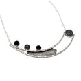 Load image into Gallery viewer, A necklace, laying flat, crafted from two long curved square wires with random black lines, connected at one end and split at the other. An angular sheet of blackened textured silver is positioned between the wires. On the right side of the top curved bar, three 10-millimeter stones are set – two black onyx and one silver mesh dome. On the left side, suspended between the ends of the curved bars, is a large bezel made of domed silver mesh. The pendant is attached to a link-in-link chain.
