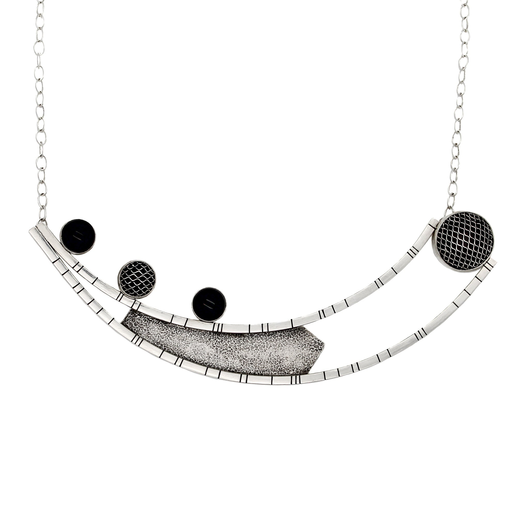 Necklace crafted from two long curved square wires with random black lines, connected at one end and split at the other. An angular sheet of blackened textured silver is positioned between the wires. On the right side of the top curved bar, three 10-millimeter stones are set – two black onyx and one silver mesh dome. On the left side, suspended between the ends of the curved bars, is a large bezel made of domed silver mesh. The pendant is attached to a link-in-link chain.