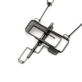 Load image into Gallery viewer, Back of of sterling silver industrial-style pendant featuring a geometric design with a combination of open rectangular frames and mesh-textured sections. A central horizontal bar intersects the piece, creating a layered, puzzle-like effect. The pendant has an oxidized, matte finish and is suspended from a chain with angular links that complement the design's structural feel. Zed Eh Design's logo can be seen on the long bar. 
