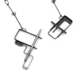 Load image into Gallery viewer, 
The image shows two segments of an industrial-style silver necklace with intricate geometric designs. The pendant sections are composed of rectangular and linear shapes, with one piece featuring a hollow, grid-patterned design and the other incorporating a bar-like element. Both pieces are connected by a chain with rectangular links. The image showcases a puzzle clasp mechanism, where the two segments interlock to form a closure. The necklace has a modern, minimalist aesthetic, with attention to bot
