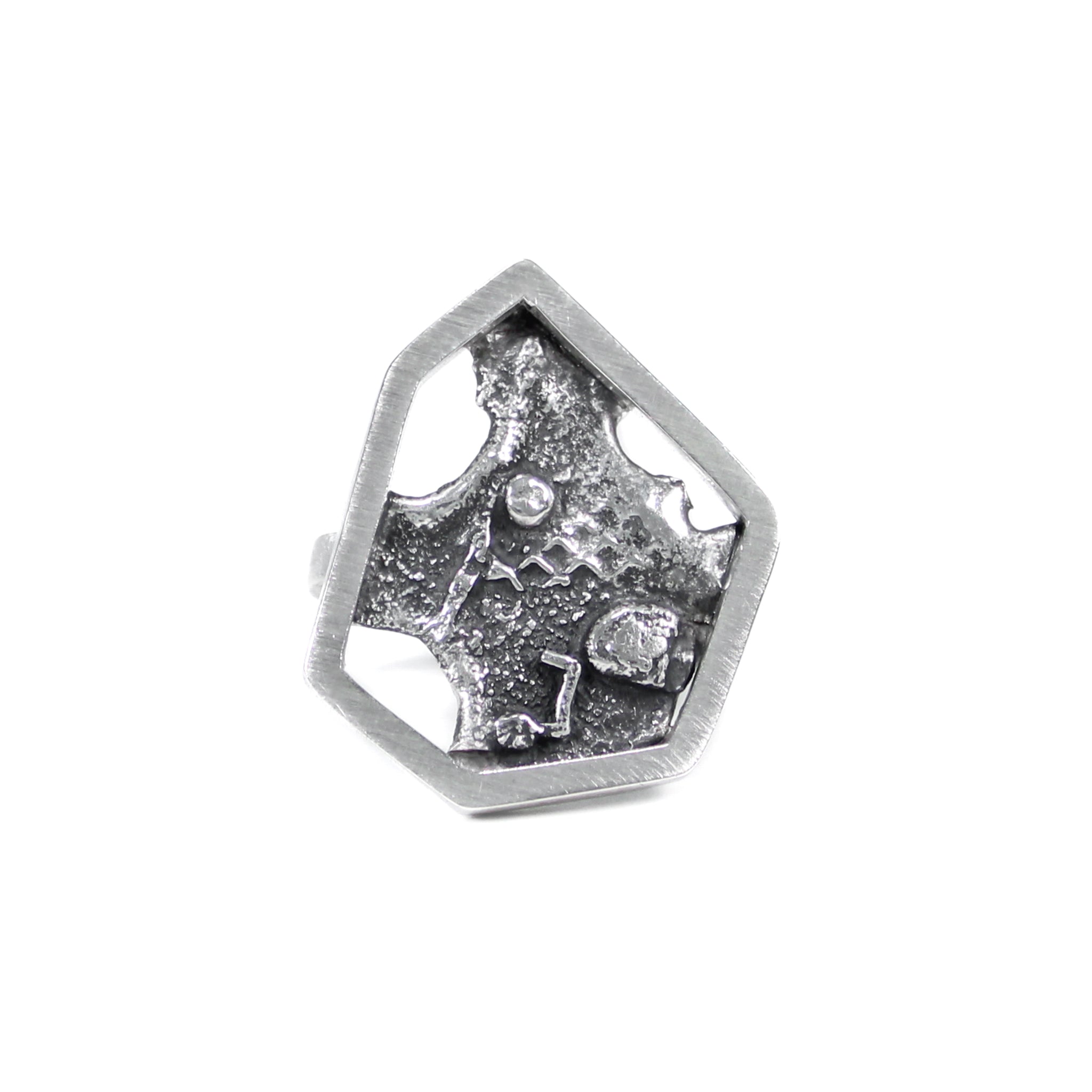 Modern brutalist inspired sterling silver ring featuring a single, asymmetric hexagon framing a blackened, melted, and fused texture backplate. View of front of ring  on white background