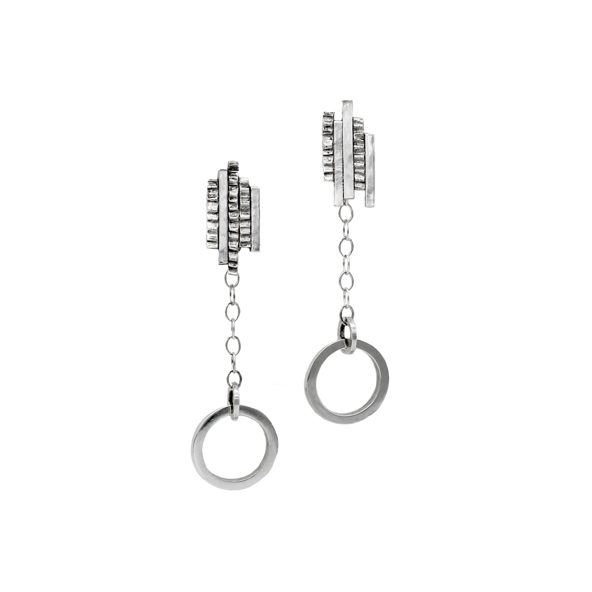 Sterling silver earrings featuring an element of textured bars lined up at irregular heights at the top of the earring, with a delicate chain leading to a smooth circular hoop. The geometric design combines rugged and polished elements, creating a modern and artistic look