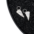 Load image into Gallery viewer, A one of a kind pair of hand fabricated silver earrings, each a rough triangular shape with a textured surface resembling ice. They are suspended from a sterling ring attached to ear posts. The earrings are seen in a black dish, with black pebbles
