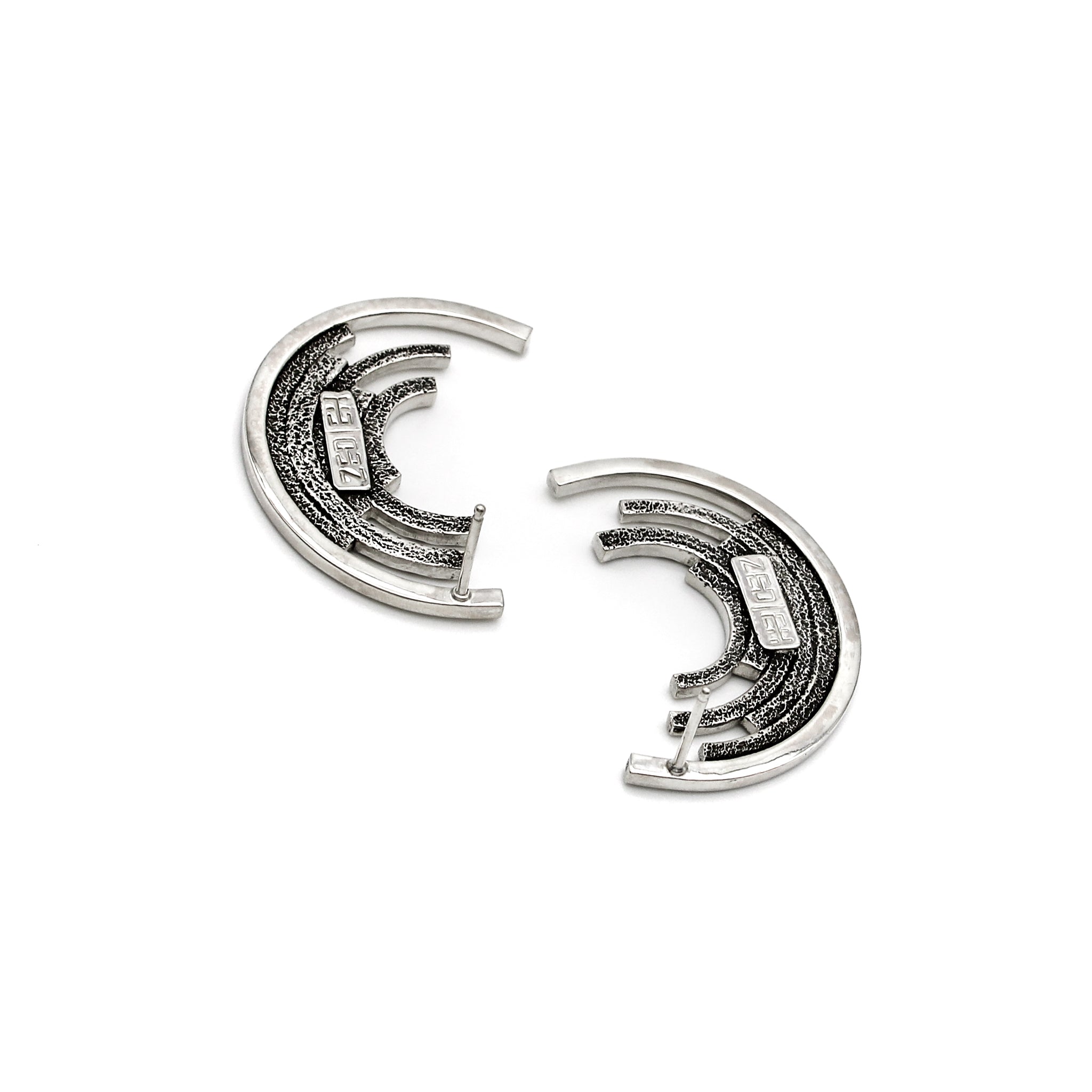 Side view showing blackened stipple texture on back of contemporary sterling silver ear studs, each with 6 concentric circles