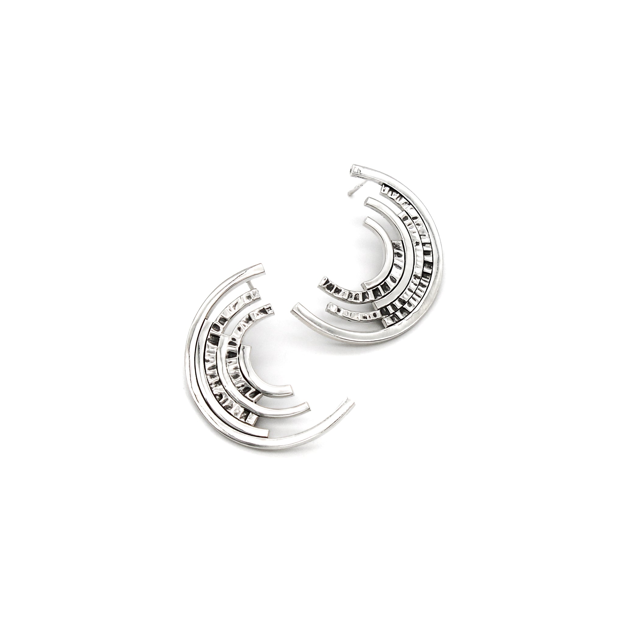 Front view of contemporary sterling silver ear studs, each with 6 asymmetric partial concentric circles with chisel textures.