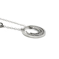 Load image into Gallery viewer, Contemporary sterling silver necklace with a prominent outer circle surrounded by five descending, staggered inner circles. The inner circles showcase varying textures, some chisel-textured and blackened for enhanced visual contrast. Suspended from a sterling silver cable chain, the pendant is complemented by four irregularly sized and textured rings positioned 1.5 inches up the chain on the right side. Necklace is laying flat, and view is from the side. 
